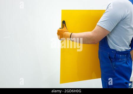 A glazier holding a yellow glass in his hands, White place for text Stock Photo