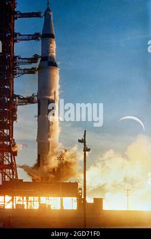 A Saturn V rocket lifts off from Cape Canaveral in Florida with the crescent moon beyond. This is Apollo 8, which put Frank Borman, James Lovell and William Anders into orbit around the moon. It launched on 21 December 1968 and was the first time man left earth orbit. Stock Photo