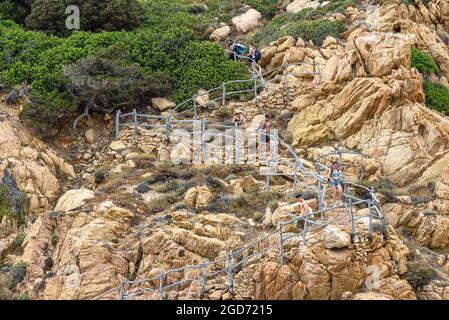 People walking on the steps next to Spiaggia di Cala li Cossi on the Costa Paradiso trail Stock Photo