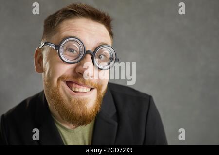 Closeup portrait of a funny crazy nerd in round frame glasses smiling at the camera Stock Photo