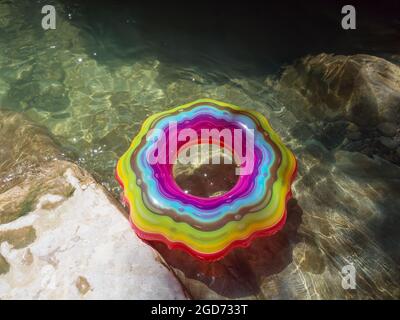 Swimming circle with multicolored patterns in a clear river with rocky bottom under the sun's rays Stock Photo