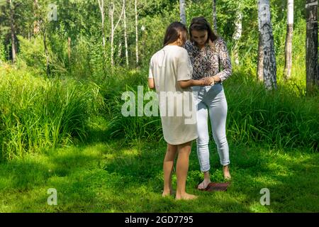 yoga coach helps a beginner to get on the sadhu board for the first time Stock Photo