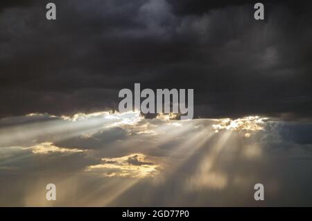 A ray of light through the clouds. Rays of light breaking through dark clouds, a dramatic sky with clouds.Bright sun during the rain.Copy space. Stock Photo