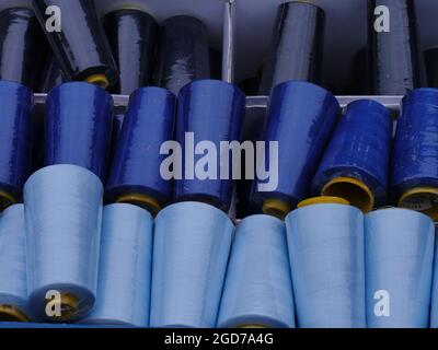 Gran rolls, partly covered with dust, in shades from light blue to dark blue, stored in a plastic box. raw material for handicraft textile work and ho Stock Photo