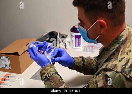 U.S. Army Sgt. 1st Class Brian Bowling, 129th Aviation Regiment critical care flight paramedic, prepares COVID-19 vaccination syringes for distribution at a medical center in Kingman, Ariz., May 12, 2021. More than 850 Arizona National Guardsmen continue to assist at vaccination sites and food banks throughout Arizona. (U.S. Air National Guard photo by Staff Sgt. Dillon Davis) Stock Photo