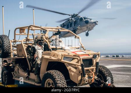 PACIFIC OCEAN (March 29, 2021) U.S. Marine Corps Sgt. Tyler Roup, left, a team leader, and Cpl. Connor Reddy, a section leader, both with Marine Medium Tiltrotor Squadron (VMM) 165 (Reinforced), 11th Marine Expeditionary Unit, sit in a Light Marine Air Defense Integrated System and watch for unmanned aerial systems while an MH-60S Sea Hawk with Helicopter Sea Combat Squadron (HSC) 21 takes off from the flight deck of the amphibious assault ship USS Essex (LHD 2) during a simulated strait transit, March 29. U.S. Navy and Marine Corps integration training provides the Essex Amphibious Ready Grou Stock Photo