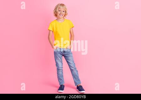 Full length photo of young small boy happy positive smile hands in pocket isolated over pink color background Stock Photo