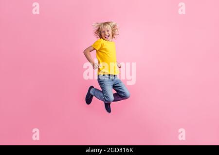 Full size profile side photo of young cheerful little boy happy positive smile jump up isolated over pink color background Stock Photo