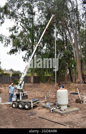 Two men pulling a water well pump and replacing the 20 foot pipe which was 26 years old - ethnic Hispanic, did the 180 foot job in a day. Stock Photo