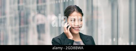 Business Asian businesswoman busy talking on smartphone calling while walking to work office commute on city street panoramic banner. Lady at airport Stock Photo