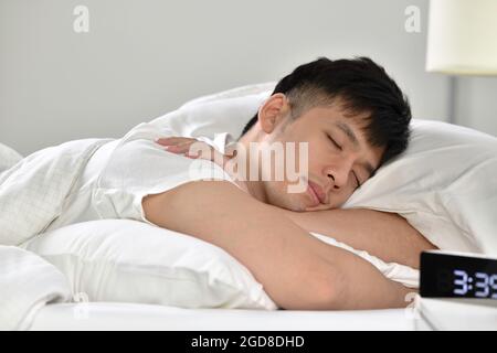 Handsome Young Asian man sleeping in bed Stock Photo