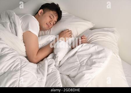 Handsome Young Asian man sleeping in bed Stock Photo