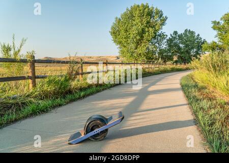 One-wheeled electric skateboard in the late summer morning on the Poudre River Trail in northern Colorado. Stock Photo