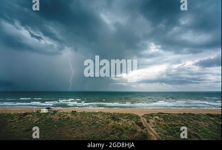 Lightning flash and dark thunderstorm over the ocean along the Mediterranean coast in Daimus, Spain Stock Photo