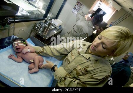 At a hospital in Kirkuk, Iraq, US Army (USA) Captain (CPT) Amber Hosier, 250th Forward Surgical Team (FST) (Airborne), Fort Lewis, Washington (WA), examines a three-hour old Iraqi girl who's trachea and esophagus has not formed properly.  Doctors from the 250th FST will jointly perform a procedure with Iraqi doctors to save her life during Operation IRAQI FREEDOM.  (USAF PHOTO BY SSGT JEFFREY A. WOLFE 031209-F-1798W-017) Stock Photo