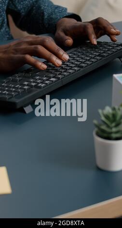 Top view of black man african american hands typing on computer keybord on a blue desk. Remote worker using PC, working from home, browsing searching online web internet communication Stock Photo