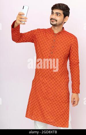 young Indian man in ethnic wear taking selfie with mobile phone. Stock Photo