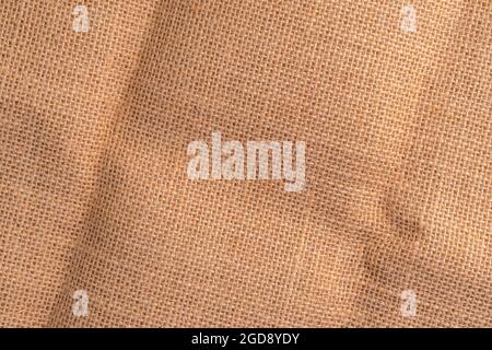 Textured folded rustic sackcloth with wrinkles. Close-up. Woven background Stock Photo