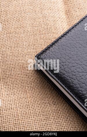 Black closed paper notebook with leather hardcover on an old textured rustic burlap surface. Copy space. Close up Stock Photo