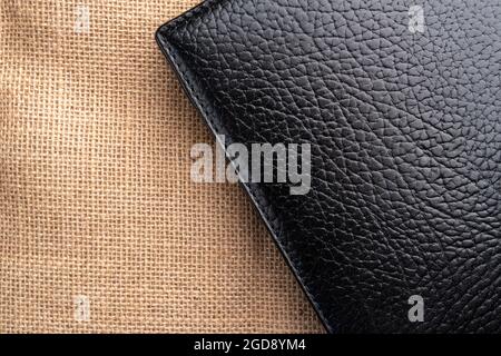 Black closed book with leather hardcover on an old textured rustic burlap surface. Copy space. Close up Stock Photo