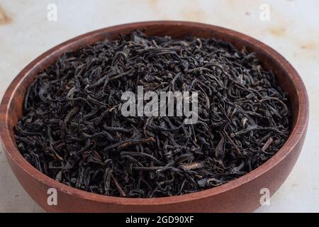 Dried Assam tea leaves in a wooden bowl Stock Photo