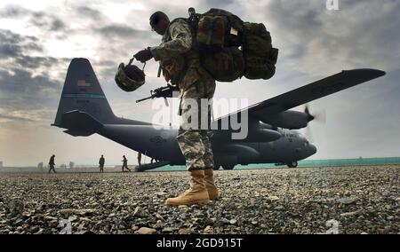 US Army (USA) Sergeant First Class (SFC) Ricky Bryant, carries his helmet, weapon and field pack, as he prepares to board a US Air Force (USAF) C-130 Hercules aircraft assigned to the 185th Airlift Squadron (AS), Oklahoma Air National Guard (OKANG) deployed to the 774th Expeditionary Airlift Squadron (EAS), during an operational re-supply mission conducted on a dirt air strip at Forward Operating Base (FOB) Salerno, Afghanistan, during Operation ENDURING FREEDOM.  (USAF PHOTO BY MSGT LANCE CHEUNG 060308-F-2907C-395) Stock Photo