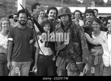 Students from the Saint George's University of Medicine pose with a member of the 82nd Airborne Division while waiting to be processed for evacuation.  The students are being evacuated from the island during the multiservice, multinational Operation URGENT FURY.  The soldier is armed with an M16A1 rifle.  (USAF PHOTO DF-SN-84-10920) Stock Photo