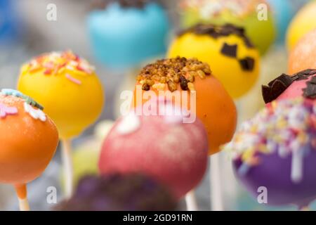 A close-up of colorful cake pops decorated with vibrant icing, sprinkles, and chocolate, creating a delightful and festive dessert display. Stock Photo