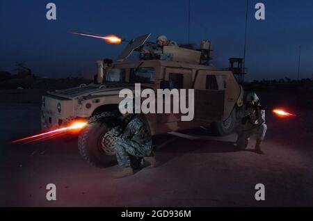 US Army (USA) Specialist Fourth Class (SPC) Ronnie Scibek (top), USA Sergeant (SGT) Glenn Santos (left) and USA SPC Kyle Hurt participate in a nighttime live fire training exercise, covering an M1114 Up-Armored High-Mobility Multipurpose Wheeled Vehicle (HMMWV), at the Iraqi Army Compound firing range on Forward Operating Base (FOB) Iskandariyah, Iraq.  The Soldiers are attached to Bravo Company (B CO), 490th Civil Affairs Battalion (CAB), 155th Brigade Combat Team (BCT), Mississippi Army National Guard (MSARNG) during Operation IRAQI FREEDOM.  (US NAVY PHOTO BY PHC EDWARD G. MARTENS 050730-N- Stock Photo