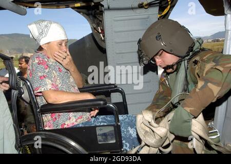 US Army (USA) Specialist Fourth Class (SPC) Ryan Becker, A Company (A CO), 1st Battalion (BN), 228th Aviation Regiment (AVN), Soto Canto Air Base (AB), Honduras (HND), secures a woman's wheel chair to the deck of a USA UH-60 Black Hawk (Blackhawk) helicopter at Soto Cano AB, Honduras.  She is being transported to Guatemala City for transport to a nearby hospital.  Personnel from Joint Task Force Bravo (JTF-B), US Southern Command (SOUTHCOM), continue to provide assistance to the government and the people of Guatemala as part of an ongoing disaster relief effort in the wake of Hurricane Wilma. Stock Photo
