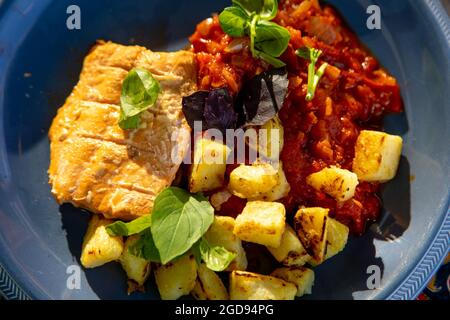 Applewood smoked salmon served with patatas bravas, lemon basil and purple basil on a plue plate Stock Photo