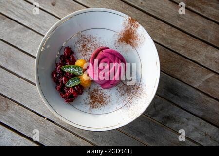 Chocolate and beetroot ice cream served with Autumn Gold raspberries, brandied blackcurrants and spearmint leaves dusted with icing sugar and cocoa Stock Photo