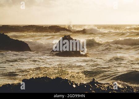 Yellow sunset lights over waves of the rough sea, Playa de la Solapa, Pajara, Fuerteventura, Canary Islands, Spain Stock Photo