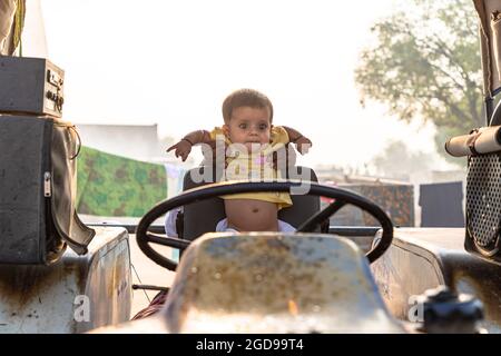 portrait of indian baby girl sitting on tractor seat. Stock Photo