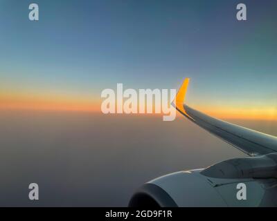 airplane wing in the golden hour flying in the sky Stock Photo