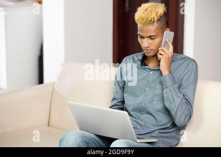 Serious programmer making phone call to coworker when working from home due to coronavirus pandemic Stock Photo