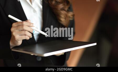 Close up hands, tablet in woman hands, working via tablet and holding stylus pen, office worker Stock Photo