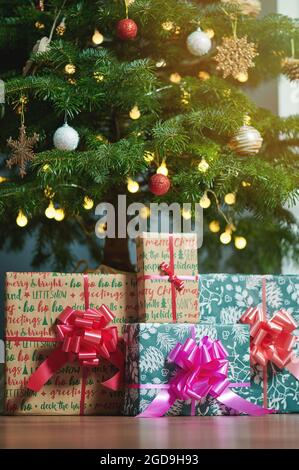 Gift boxes under bright Christmas tree on wooden floor Stock Photo