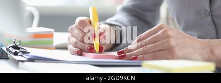 Business woman with red manicure writing with pen on paper stickers closeup Stock Photo