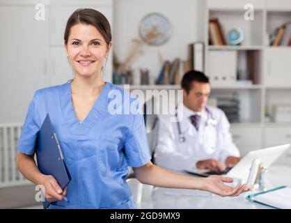 Female doctor making welcome gesture, politely inviting patient in office Stock Photo