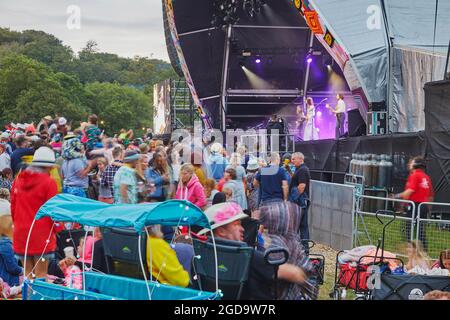 A dusk view of crowds of spectators in front of the main stage at Camp Bestival, a family-friendly annual music festival in Lulworth, Dorset, UK Stock Photo