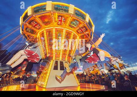 A merry-go-round at dusk, blurred motion with long exposure; Camp Bestival, Lulworth, Dorset, Great Britain. Stock Photo