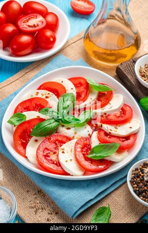 Caprese salad with tomatoes, mozzarella and basil on a blue background. Stock Photo
