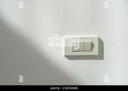 White switch power on a white wall with light and shadow contrast. Stock Photo