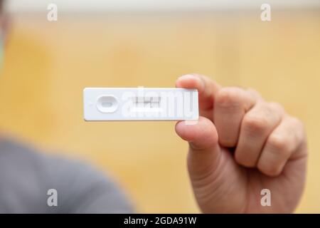 Coronavirus negative result rapid test, self testing at home, Man hand holding covid 19, kit for detecting antibodies and immunity. Closeup view, sele Stock Photo
