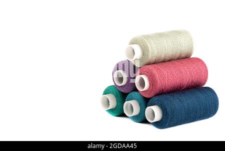 Pyramid from spools of threads of different colors on a white background. The coils are on the right side of the canvas. Stock Photo