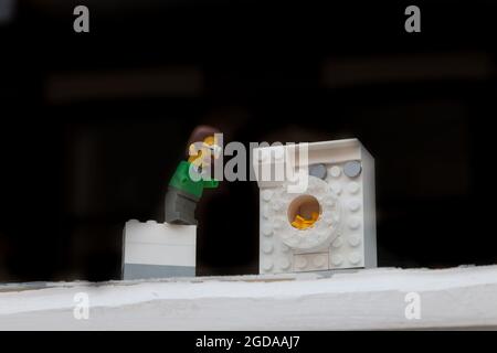 A lego minifigure waits by a washing machine waiting for his hands to wash. During the Covid-19 pandemic the public were asked to wash their hands. Stock Photo