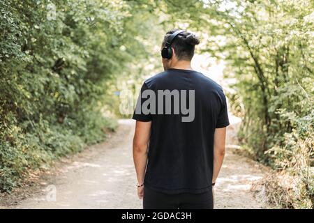 Young man listening to music out in the nature. Back view Stock Photo