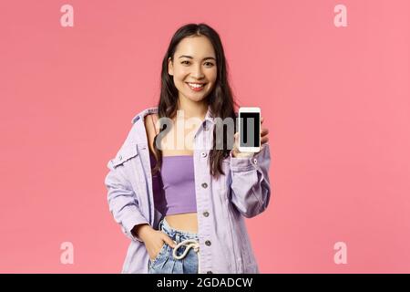 Online lifestyle, people and beauty concept. Portrait of modern stylish hipster girl, korean female showing you mobile phone display, recommend app or Stock Photo