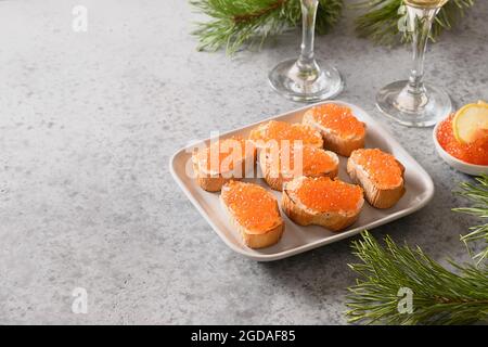 Appetizer canape of ciabatta with red caviar on gray stone table. Christmas, New Year holidays party. Festive food. Close up. Stock Photo